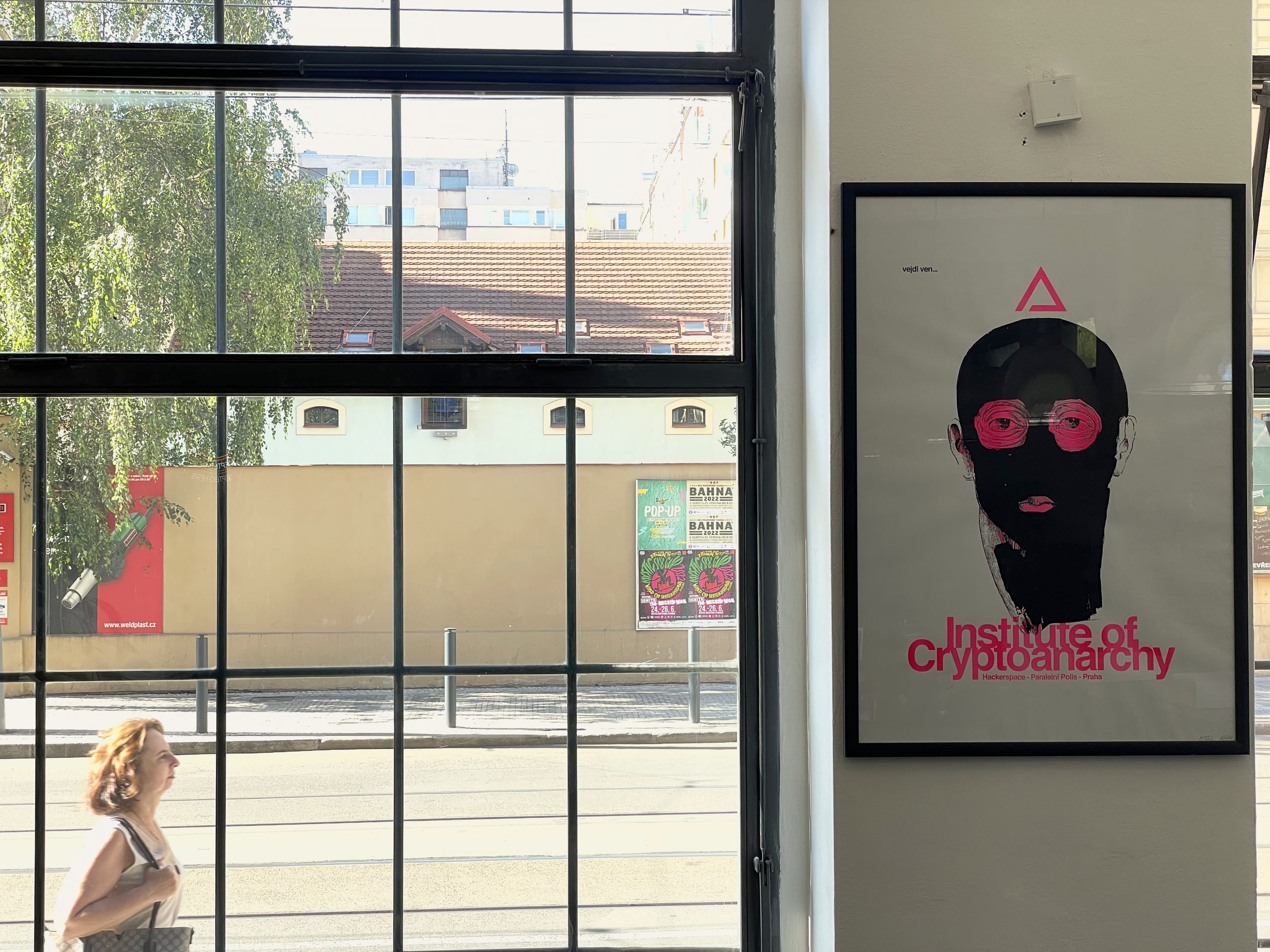 Institute of Cryptoanarchy poster on the wall of Paralelní Polis, with the MSC poster on the official billboard behind
